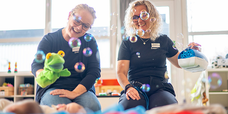 Två pedagoger från öppna förskolan leker med ett litet barn