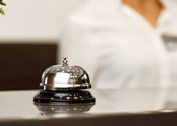 Serviceklocka på hoteldisk framför receptionist.
