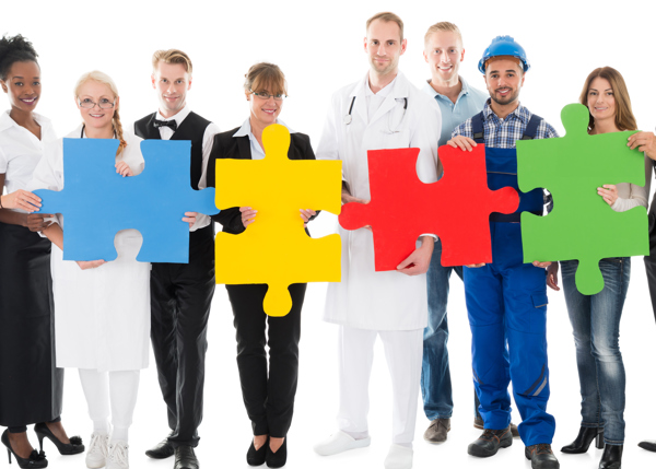 Grupp med människor med olika yrken håller i stora pusselbitar i olika färger